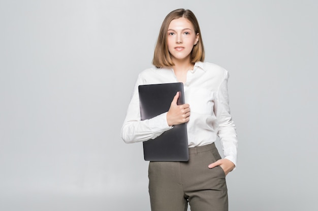 Mulher de negócios bem-sucedida segurando um laptop sobre uma parede branca