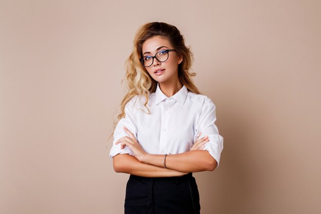 Mulher de negócios bem sucedido atraente com sorriso sincero olhando. Professor ou empregado. Parede bege.