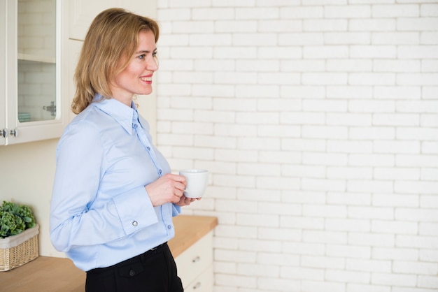 Mulher de negócios bonita em pé com uma xícara de café