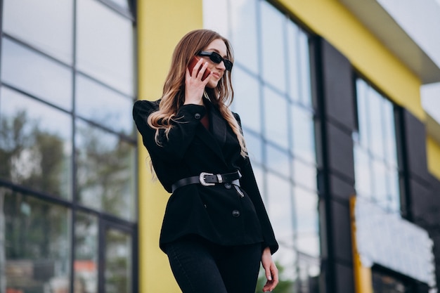 Mulher de negócios bonita jovem pelo centro do escritório, usando o telefone