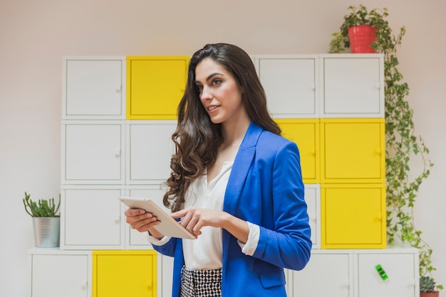 Mulher de negócios bonita que prende uma tabuleta no escritório