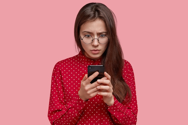 Foto grátis mulher de negócios chocada olha com surpresa para a tela do smartphone, lê notícias negativas na internet e recebe mensagem