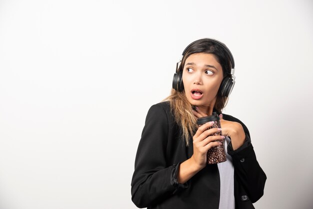 Mulher de negócios com copo e fones de ouvido.