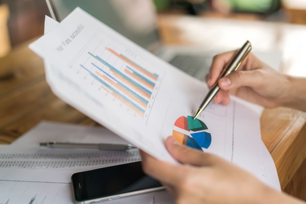 Mulher de negócios com gráficos financeiros e laptop na mesa.