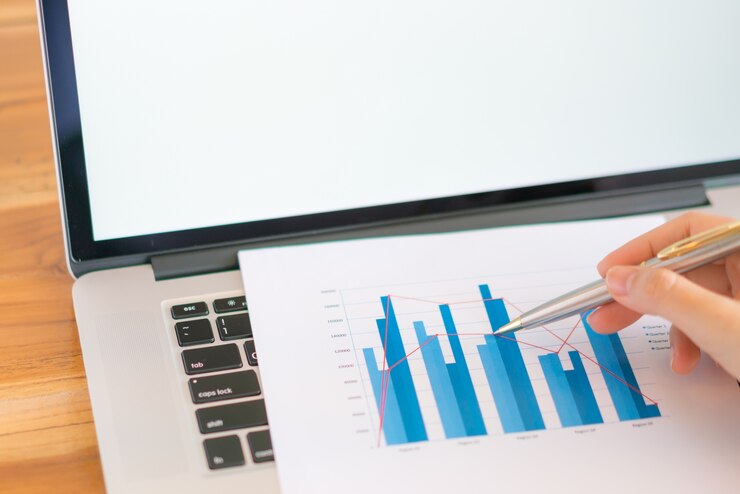 Foto grátis mulher de negócios com gráficos financeiros e laptop na mesa.