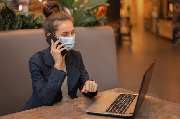 Mulher de negócios com máscara médica trabalhando em laptop