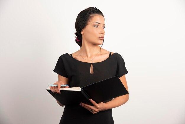 Mulher de negócios com notebook posando na parede branca.