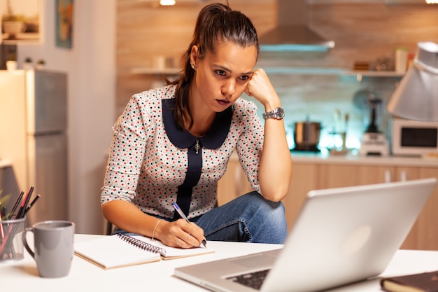 Mulher de negócios concentrada tentando terminar um projeto de trabalho à meia-noite. Funcionário usando tecnologia moderna à meia-noite fazendo horas extras para trabalho, negócios, ocupado, carreira, rede, estilo de vida, sem fio