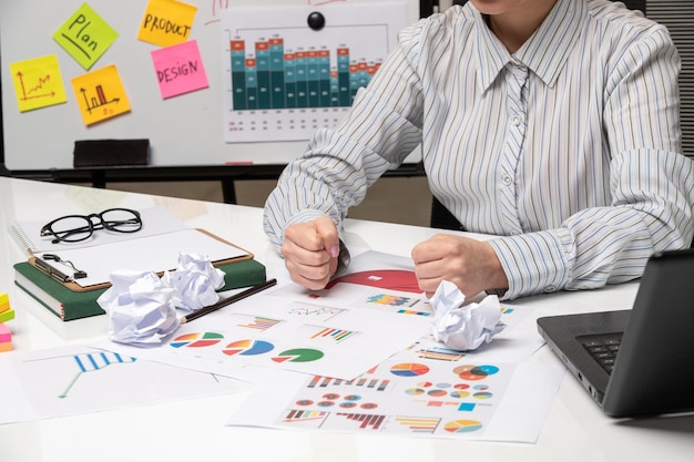 Mulher de negócios de marketing em camisa listrada no escritório com óculos na mesa segurando os punhos apertados