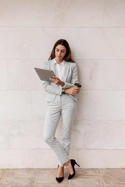 Mulher de negócios elegante segurando tablet e xícara de café