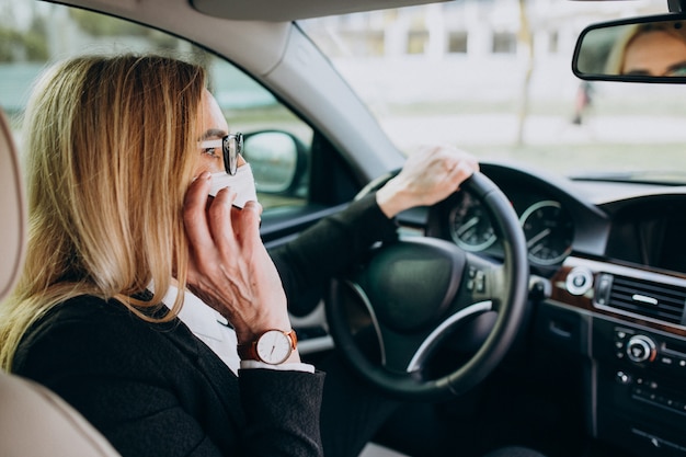 Mulher de negócios em máscara de proteção, sentado dentro de um carro