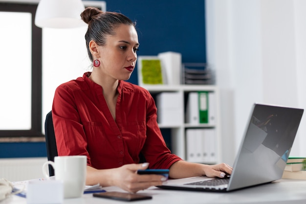 Mulher de negócios em um escritório corporativo segurando um cartão de crédito