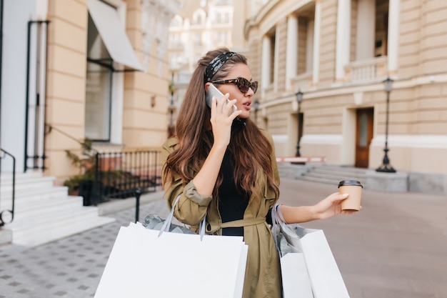 Mulher de negócios encantadora falando ao telefone enquanto faz compras