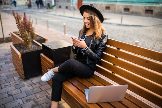Mulher de negócios estudante garota sentada em um banco de madeira na cidade no parque no outono