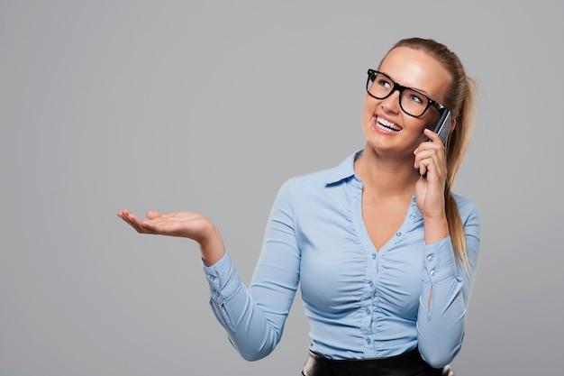 Foto grátis mulher de negócios falando no celular e mostrando no espaço da cópia