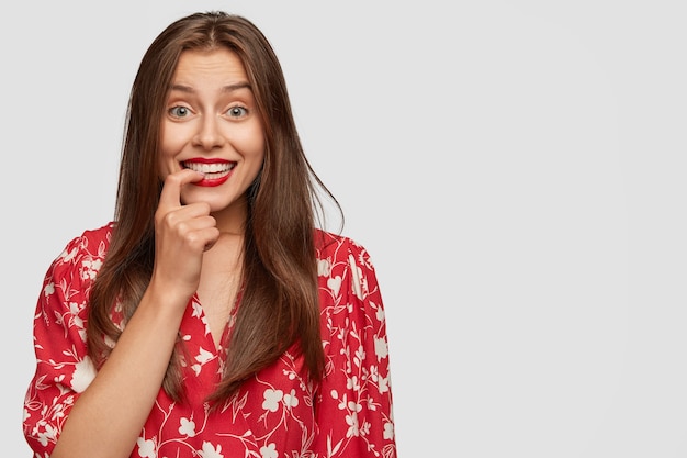 Mulher de negócios feliz e inexperiente sorri positivamente, mantendo o dedo nos dentes