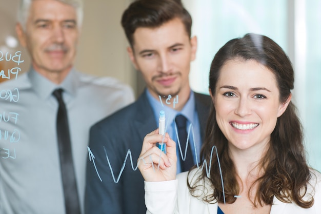 Mulher de negócios feliz Gráfico de desenho no visor de vidro