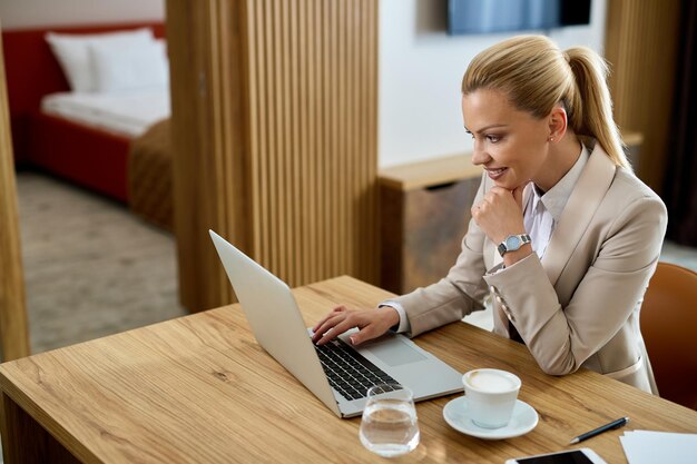 Mulher de negócios feliz lendo um e-mail enquanto está em um quarto de hotel