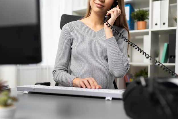 Mulher de negócios grávida ao telefone em sua mesa de escritório