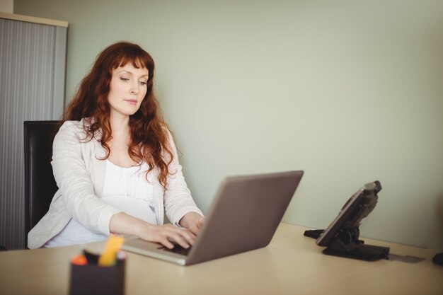 Mulher de negócios grávida usando laptop