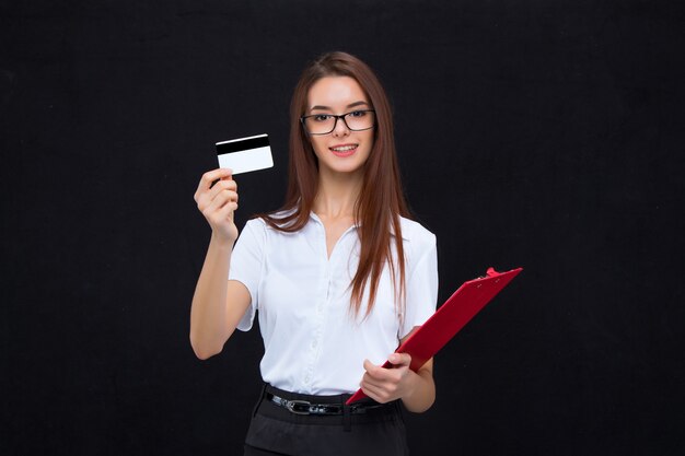 Mulher de negócios jovem de óculos com cartão de crédito e prancheta para anotações