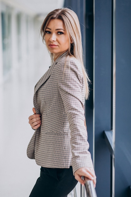 Mulher de negócios jovem em pé junto à janela em um escritório