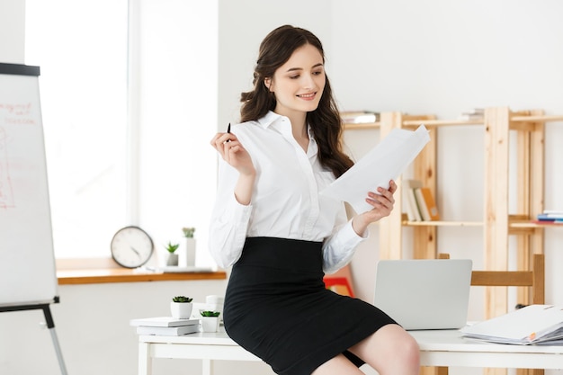 Mulher de negócios jovem feliz ou secretária segurando um documento em um escritório moderno
