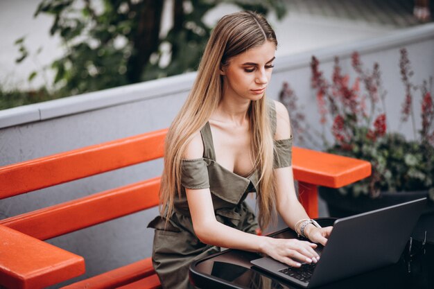 Mulher de negócios jovem trabalhando no laptop fora em um café