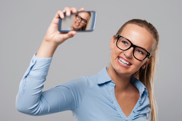 Mulher de negócios loira de óculos tirando foto de auto-retrato