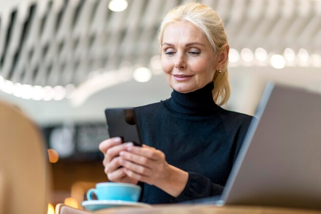 Mulher de negócios mais velha trabalhando em smartphone e laptop