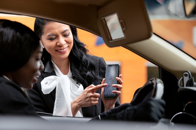 Mulher de negócios mostrando seu aplicativo de smartphone para o motorista de táxi