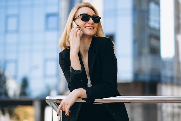 Foto grátis mulher de negócios pelo arranha-céu usando o telefone