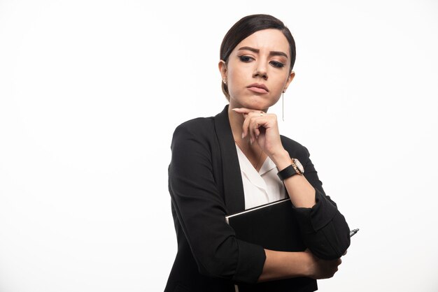 Mulher de negócios posando com o caderno na parede branca.