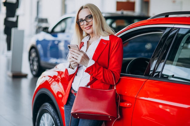 Mulher de negócios, procurando um automóvel móvel em uma sala de exposições de carros