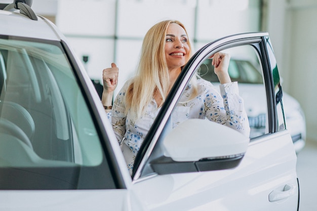 Mulher de negócios, procurando um automóvel móvel em uma sala de exposições de carros