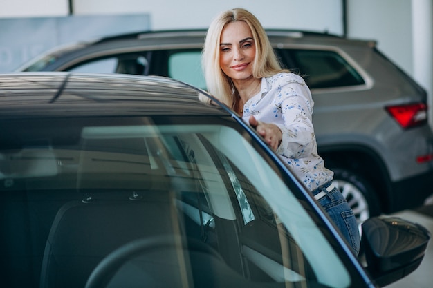 Mulher de negócios, procurando um automóvel móvel em uma sala de exposições de carros