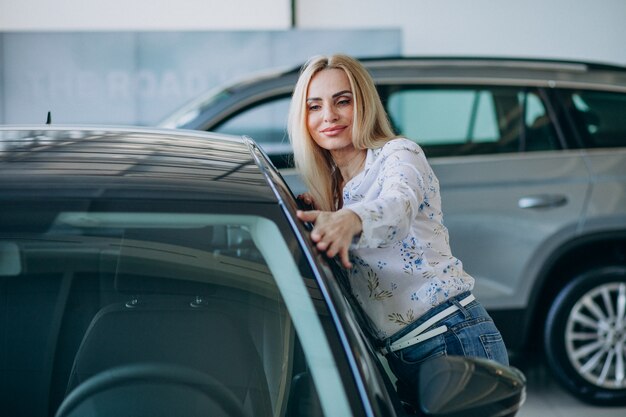 Mulher de negócios, procurando um automóvel móvel em uma sala de exposições de carros