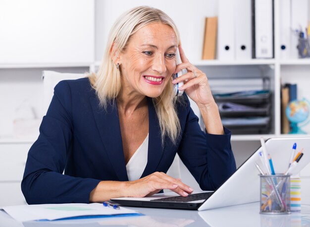 Mulher de negócios que conversa por telefone no escritório