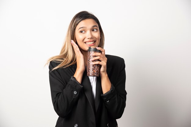 Mulher de negócios, segurando a taça e posando na parede branca.