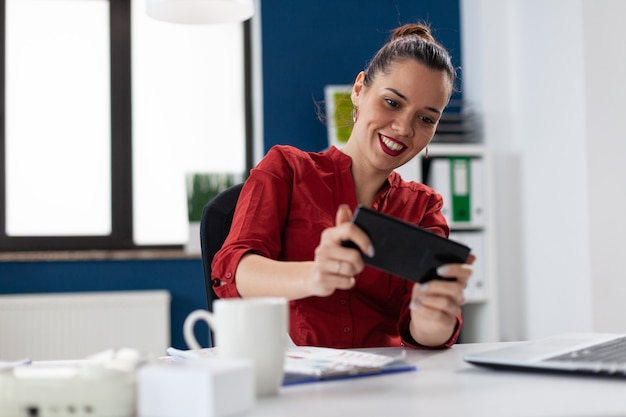 Mulher de negócios sentada na mesa de um escritório corporativo jogando videogame