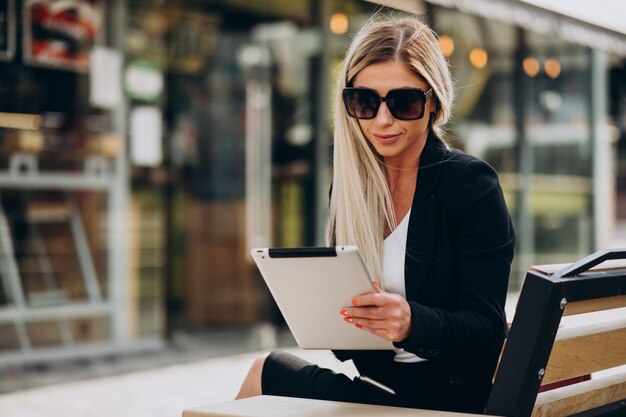 Mulher de negócios sentada no banco e trabalhando em um tablet