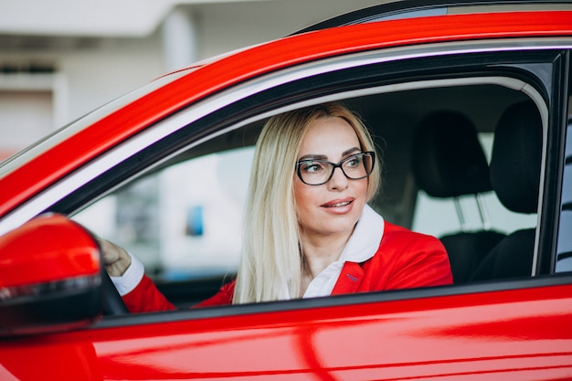 Mulher de negócios, sentado em um carro novo em uma sala de exposições