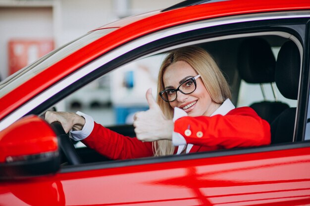 Mulher de negócios, sentado em um carro novo em uma sala de exposições