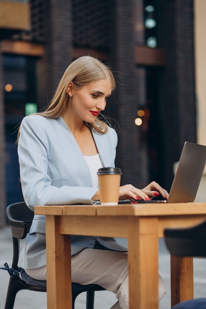 Mulher de negócios trabalhando em um computador em um café e bebendo café