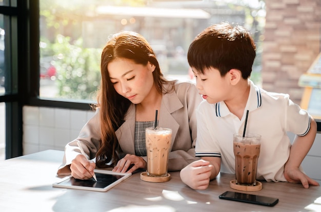 Mulher de negócios trabalhando online no café com criança. estilo de vida familiar asiático com celular e tablet digital.