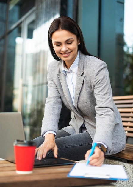 Mulher de negócios usando laptop enquanto toma café ao ar livre