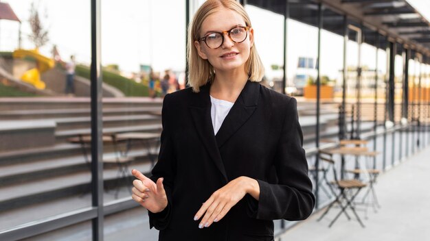 Mulher de negócios usando linguagem de sinais ao ar livre no trabalho