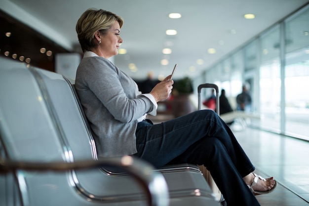 Foto grátis mulher de negócios usando telefone celular na sala de espera