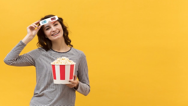 Mulher de óculos 3d segurando um balde com pipoca com espaço de cópia
