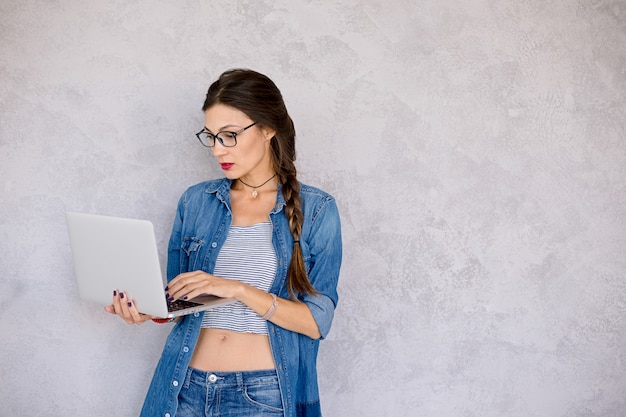 Mulher de óculos em pé focado para o laptop